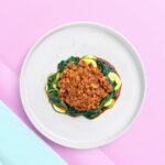 Banner van Keto Spaghetti Bolognese met Courgette en Spinazie, geserveerd op een wit bord tegen een pastelkleurige achtergrond.