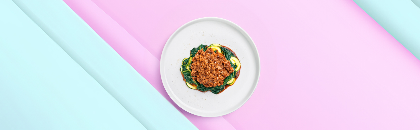 Banner van Keto Spaghetti Bolognese met Courgette en Spinazie, geserveerd op een wit bord tegen een pastelkleurige achtergrond.