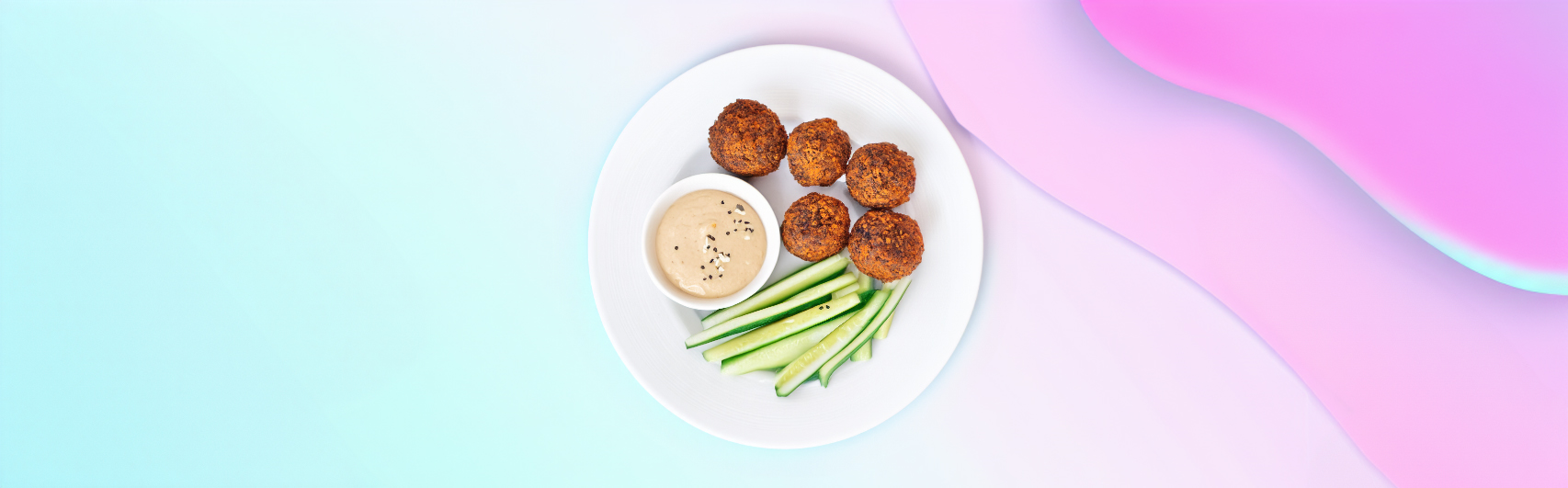 Banner van Keto falafel balletjes geserveerd met een frisse komkommersalade en tahinisaus, gepresenteerd op een wit bord tegen een achtergrond van zachte pastelkleuren.