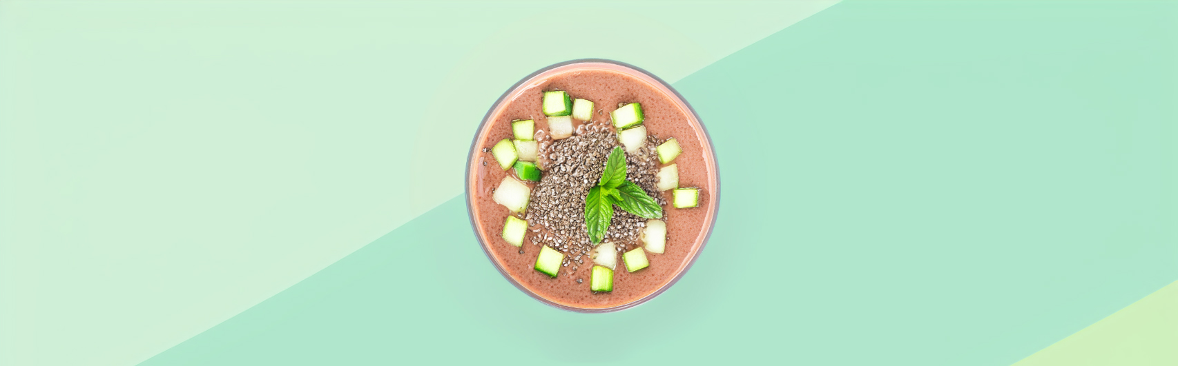 Banner van een Luxe Keto Chocolade Smoothie met Komkommer en Chiazaad, stijlvol gepresenteerd in een glazen kom tegen een pastelkleurige achtergrond.