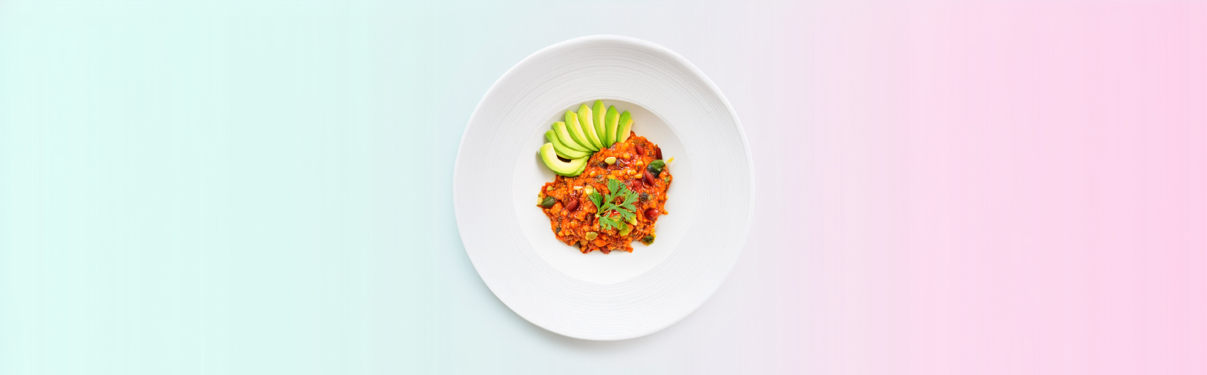 Banner van een Smaakvolle Keto Chili met Avocado en Courgette, smakelijk geserveerd in een witte schaal, geaccentueerd tegen een roze en groene achtergrond.