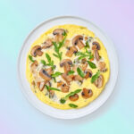 Banner van een heerlijke Keto omelet rijk bestrooid met fijne kruiden, versierd met rucola en champignons, gepresenteerd op een wit bord tegen een achtergrond met pastelkleurige diagonale strepen.